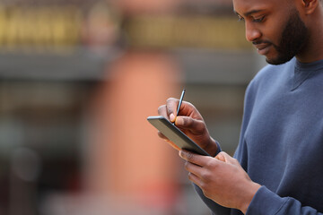 Man with black skin writing on phone with digital pen