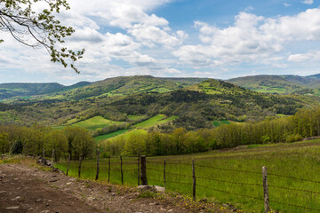 Fototapeta na wymiar Panorama sur une vallée verdoyante avec ses belles collines boisées au printemps sur le chemin de randonnée de Boudes Chalus dans le puy de dôme