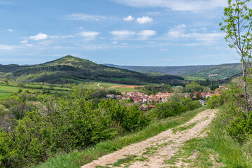 Fototapeta na wymiar Petit village de Boudes avec ses petit monts verdoyants depuis de chemin de randonnée de Boudes Chalus dans le puy de dôme par une belle journée de printemps
