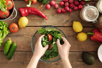 Female hands cooking fresh salad. Set of various vegetables for preparing healthy summer food on wooden table top view