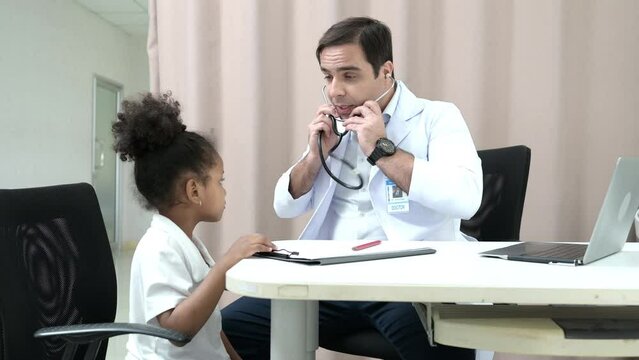 A doctor at an international hospital Trying to check up of a mischievous child in the hospital's OPD examination room.