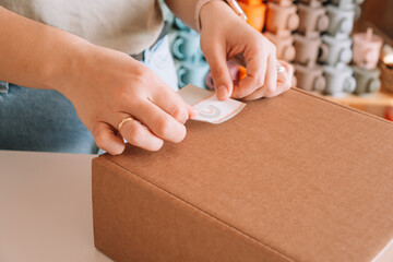 Cropped photo of businesswoman hands packing, preparing parcel for delivery package to buyer,...