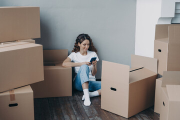 Happy young european woman with smartphone is packing boxes. Shipping service order concept.