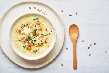Vegan cauliflower soup on white background. Healthy vegan cauliflower soup served in bowl on white table.
