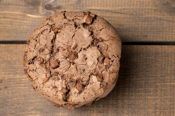 brown chocolate chip cookie large poan.  On a black background. Chocolate chip cookies with brown chocolate chips are placed on a wooden table.