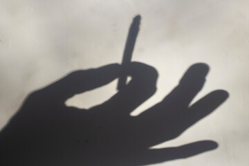 Fototapeta na wymiar Shadow of a cigarette in hand. Smoking is harmful to your health.