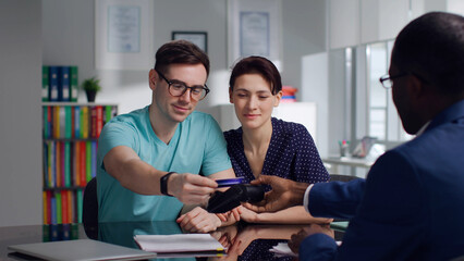 Happy young couple pay insurance fees with credit card in modern office