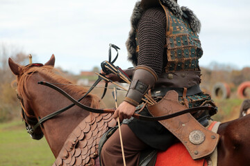 A Turkish soldier in traditional clothing is riding a brown horse. An archer in the old Turkish...