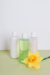 Fototapeta na wymiar Natural cosmetics, shower gel, bath foam, body lotion with yellow daffodil flower. Spa and wellness concept