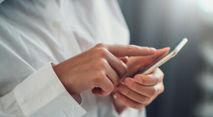 Smartphone in female hands. Girl using mobile phone app for texting message or browsing internet, close up.