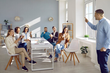 Overjoyed diverse businesspeople applaud thanking male team leader for presentation. Smiling employees or workers clap hands greeting man coach or presenter at meeting. Training.