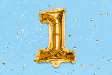 The number of the balloon made of golden foil, the number one on a blue background with sequins....