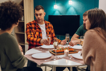 Group of friends enjoying dinner while sitting at the kitchen table together