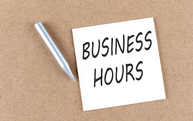 BUSINESS HOURS text on sticky note on a cork board with pencil ,