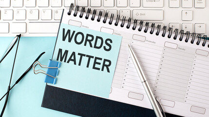 WORDS MATTER text on blue sticker on planning and keyboard,blue background