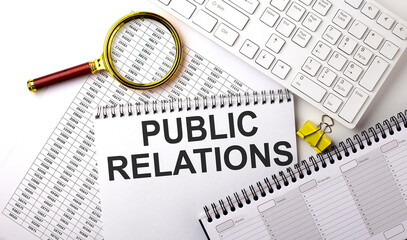 PUBLIC RELATIONS text written on a notebook on chart with keyboard and planning
