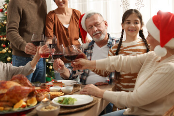 Happy family clinking glasses of drinks at festive dinner indoors. Christmas celebration