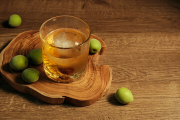 Homemade plum wine or UMESHU and green plums on wooden plate.