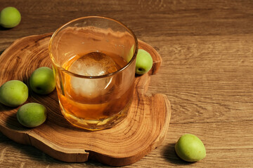 Homemade plum wine or UMESHU and green plums on wooden plate.
