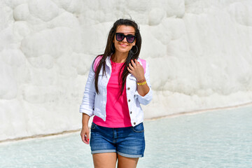 Beautiful Smiling   Happy  brunette Tourist   Woman walking on the turqouise pool of travertines - Pamukkale, Traveler woman in Travertine pool famous UNESCO place in Turkey. Pamukkale Cotton Castle 