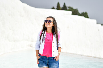 Beautiful Smiling   Happy  brunette Tourist   Woman walking on the turqouise pool of travertines - Pamukkale, Traveler woman in Travertine pool famous UNESCO place in Turkey. Pamukkale Cotton Castle 