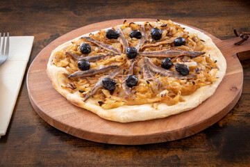 pissaladière cooked on a wooden board on a table