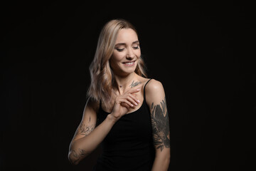 Fototapeta premium Beautiful woman with tattoos on body against black background