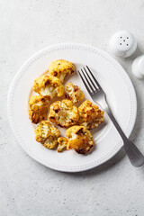 Baked crispy spicy cauliflower on white plate. Cooking healthy food concept.
