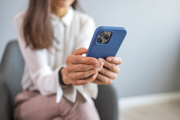 Businesswoman with mobile phone in hand. Asian business woman texting on her cell phone at the office and looking happy - communications concepts