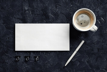 Obraz na płótnie Canvas Blank envelope, coffee cup, pen and metal clips on black plaster background. Branding mock up. Top view.