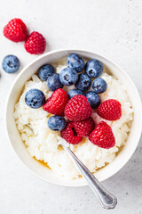 Rice pudding with berries and butter. Porridge bowl with raspberries and blueberries.