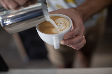 Barista pouring milk into a mug of coffee