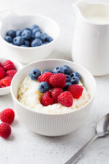 Rice pudding with berries and butter. Porridge bowl with raspberries and blueberries.