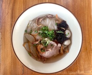 Top view white noodle soup with  pork meat, fish ball and seaweed on wooden table.