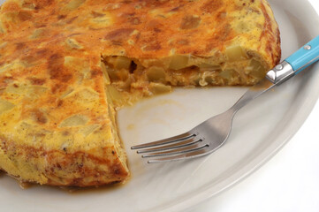 Omelette espagnole dans une assiette avec une part coupée avec une fourchette en gros plan