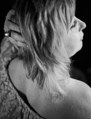 Studio black and white portrait of a beautiful woman in profile, half-turn in a summer dress and with a large ring on her hand.