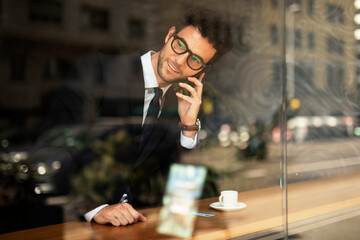 Handsome businessman using the phone in cafe. Young elegance man enjoy in fresh coffee.