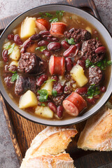 Hearty Portuguese Stone Soup served with bread closeup in the plate on the table. Vertical top view from above