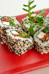 Vegetable, vegetarian sesame sushi roll in a red plate on a gray background