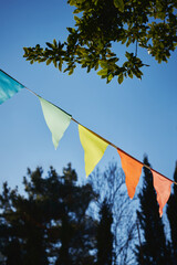 Festive fabric garlands against the blue sky in summer. The concept of celebration, rest, joy and happiness. Vertical photo.