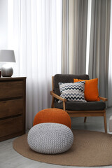 Stylish comfortable poufs near armchair in room. Home design