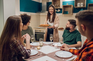 Group of friends enjoying dinner while sitting at the kitchen table together