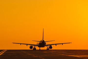 Naklejka na ściany i meble Silhouette of air plane landing at sunset with beautiful red sky in background. Evacuation
