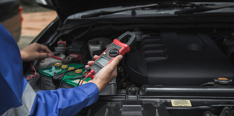 A technician is checking the car battery for availability.
