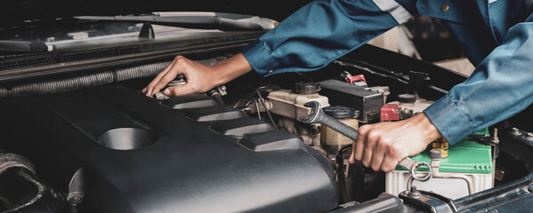 Car mechanic working on car engine, car maintenance concept.