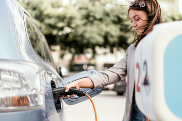 A woman charging an electric car in urban settings