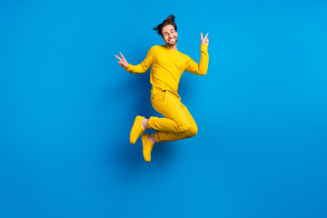 Fototapeta na wymiar Full length body size view of attractive cheerful guy jumping showing v-sign isolated over bright blue color background