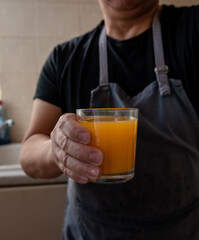 A person holding a glass of freshly squeezed orange juice.