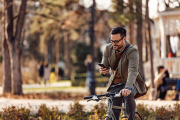 Smiling man checking his phone while riding a bike.