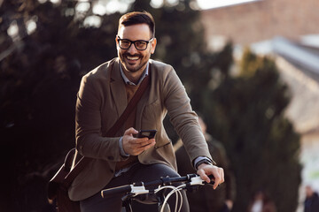 Portrait of elegant businessman, going to work by bike, using his mobile.